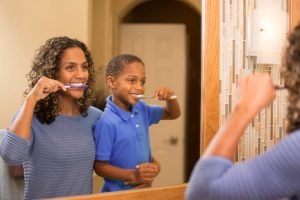 mother teaching young son to brush his teeth