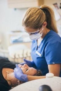 Dentist With Face Mask Looking Down on Patient