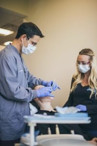 Dentist examines patient with dental assistant